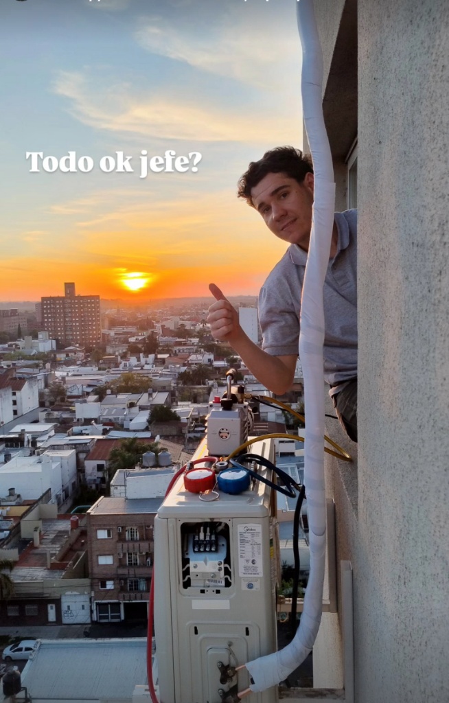 Técnico trabajando en altura con aire acondicionado al atardecer